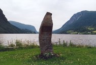 The millennium stone at Holsen. The material for the memorial stone and the stone seats was found at Svorakråa in the east of the district. The spot is beautifully situated at the river mouth at the upper end of the Holsen lake.