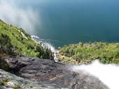 View from the top of the waterfall with a moderate flow of water. The Kvinnefossen waterfall is a fine tourist attraction. Occasionally cruise boats and sightseeing boats take a detour from their normal course and go close up into the bay.