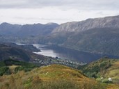 On the north side of the Dalsfjord, there is a glimpse of the so-called "geitestien" (goat path), the name given the unfinished road from Eikenes to Otterstein. The picture was taken from Grøneholten, south-east of Dale. To the left in the picture, the ferry quay at Eikenes.