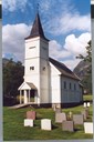 Haukedalen church is a basilica church in timber framework painted white, with its steeple above the porch to the west.
