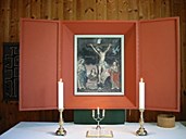 The altarpiece and the altar. On the altar are two brass candlesticks and a small three-branched candelabra in silver. The theme of the altarpiece is Christ on the cross, and three female worshippers, most likely Mary, Christ's mother, Mary Magdalene, and Salome.