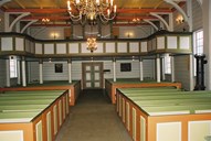 From the interior of the nave seen towards the gallery and the porch. After the 1963 renovation, the gallery was painted in shades of red, green, grey and yellow. The organ dates from 1913 and has five registers. It was built by 'Olsen & Jørgensen', and is a gift from emigrated people from this village to America. Under the gallery hang two paintings from the early 18th century.