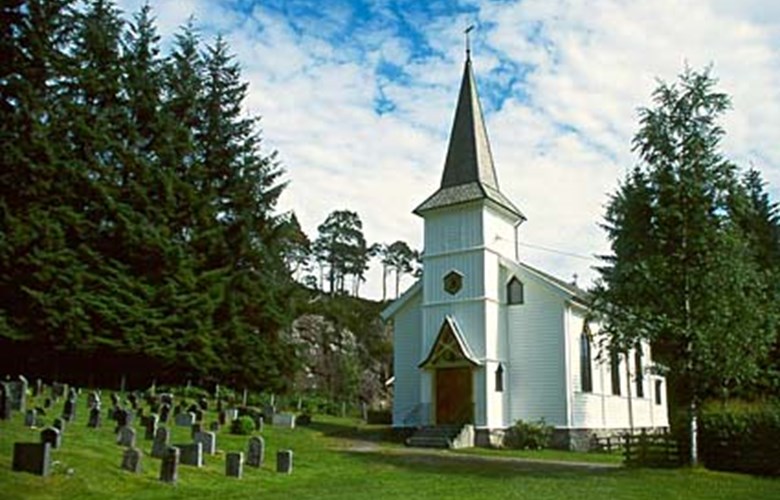 The fine church site has a sheltered location close to the bay of Hjellvika and a pine forest. 