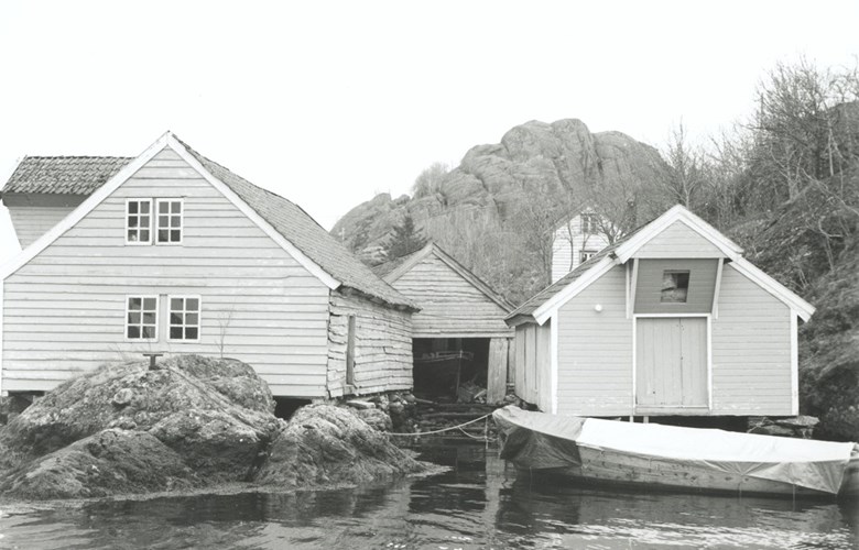 Sea warehouse at Steindalen, Solund. The house to the right was built with materials from an earlier yacht house at Rånøy. In the middle a boathouse. The house to the left is a saltery from Batalden. The house is quite wide and is divided along its length with a solid cross beam in the middle, with strong posts. Bends and knee brackets support the roof beams. This house is now gone.