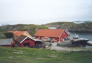 Boathouse and sea warehouse at Gåsvær. The yellow building is the characteristic old house. To the left is the boathouse, the only one of its kind still standing in Solund. It was renovated a few years ago and has now other functions. The exterior was not changed.<br />
Asbjørn Gåsvær writes that the sloop at Gåsvær could be around 35 feet long, and had no deck. She loaded 50 barrels of fish. In the wing there was room for four to sleep. His grandfather thought it best to unload the whole cargo at Lærdal. The trip east along the fjord could take more than a week if the weather was unfavourable, with a good westerly wind, about 24 hours. They always towed a dinghy.<br />
They stored the sloop in the boathouse with the stern inward, and they cut the beams some to make room for her. Her last transport task was to bring stone for the foundations of the warehouse. This job left her so weak that they decided to scrap her, around 1914.