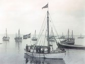 Fishing-boats at anchor near Andenes around 1910. The boat in the foreground was owned by the brothers Rasmus, Andreas, and Søren Strand, who moved from Barøy in the 1880s. This is their first motorized boat, but it is also rigged for sail. Probably the picture was taken a short time after they acquired the boat.