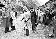 The happy moment: opening of the road Hardbakke - Krakhella. The county governor Nikolai Schei cuts the tape on 19 September 1960. To the left the mayor Henrik Nybø and the bailiff Mathiesen. At this point in time, the whole length of the road could not be used. It can be seen that it lacks the top gravel, and the width of the road is not particularly impressing. The ceremony is taking place up the road from Hardbakke.