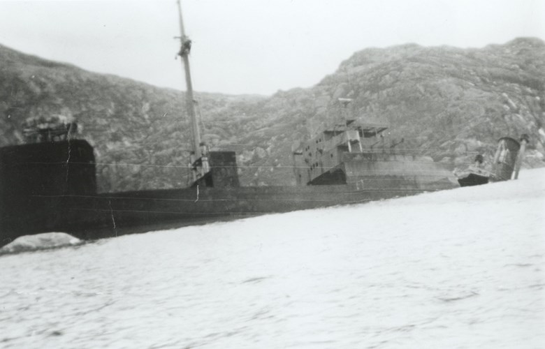 The burnt-out ship. The inclination of the funnel shows that the ship is about to break into two. Later it was easier to get onboard since the boats could go alongside where the deck was split. The great quantities of potatoes in the holds were not accessible.