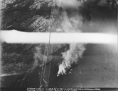 An English pilot took this picture during the battle at Krakhellesundet. The smoke from the fjord shows where the "Ferndale" and the "Parat" are burning. The lighthouse at Seglsteinen can be seen. Some entered lifeboats, others fought hopelessly against the flames.