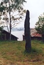 The menhir now stands on a flat meadow above a row of boathouses.