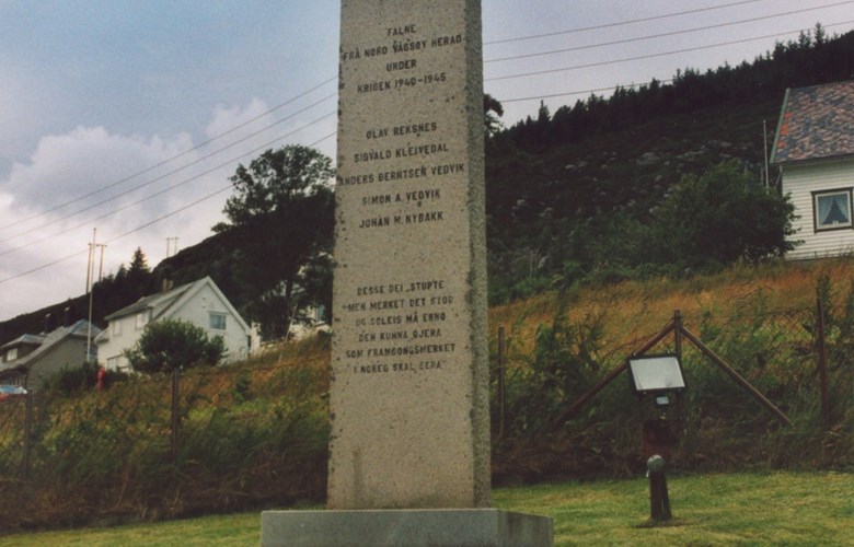 The memorial stone for the men from Nord-Vågsøy who died in the war stands on a slope above the road to the Nord-Vågsøy church at Røysaneset. From its base it measures 278 centimetres in height, 73 by 23 centimetres at the base and slightly narrower at the top.