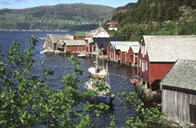 There is still some fishing activity in the bay of Torskangerpollen, but it can hardly match what it was like in the period between 1890 and 1920. Here we see a row of warehouses, ocean cottages and boathouses seen from the innermost part of the bay with Kvalheim in the background.