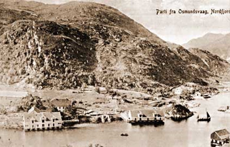 The trading post of Osmundsvåg with two big sea warehouses, "borgstove" (accommodation for servants and guests), and the main residence with its three storeys and 30 rooms. One of the sea warehouses was sold and torn down when the trading activities came to an end, whereas the other was destroyed by a spring tide. Down to the left in the picture is the building called "Sivertbuda" and the boat "Sjøbrodden".