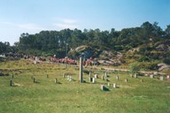 The 17 May procession at Mjømna in 1999 on its way to the church where there every year is a ceremony at the memorial stone on the grave of Konrad Byrknes. The stone is some three metres high, 55 centimetres wide and 23 centimetres thick.