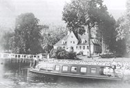 Askelund In the early 1900's. The photo shows the beautiful harmony between the building, the garden, the pier and the farmyard tree. The oval veranda was cast by Danielsen and Scholz. The two small dormers and the round window in the ridge were probably built when Angell lived here. The boat in the foreground is probably 'Heimchen' which was much used by the Scholz family.