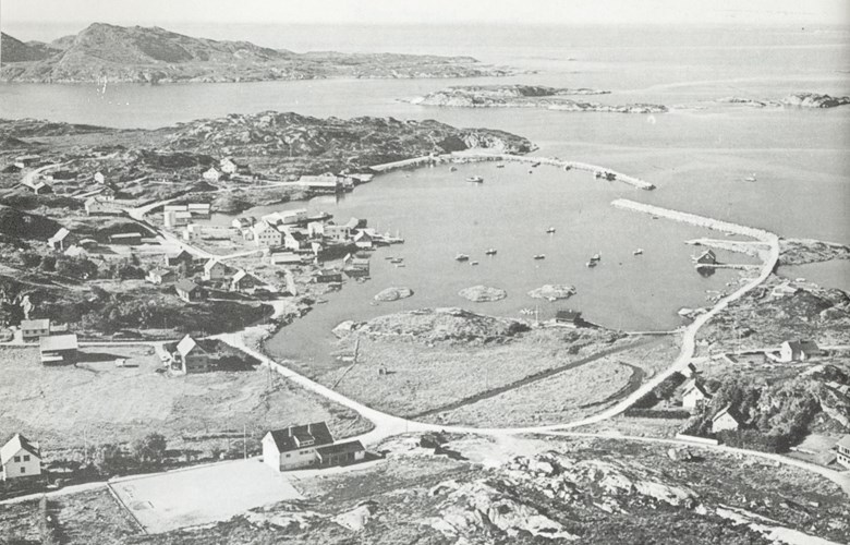 In 1930, Løkeland moved to Herland on the west side of Atløy and built a residential house and a business there. The picture shows Herland in the 1970s with the cannery centrally located on the harbour. The breakwaters were built in 